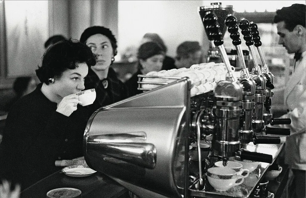 تصویر یک کافه در دهه ۱۹۵۰ با دستگاههای اهرمی گاجیا و مشتریانی که در حال نوشیدن اسپرسو هستند