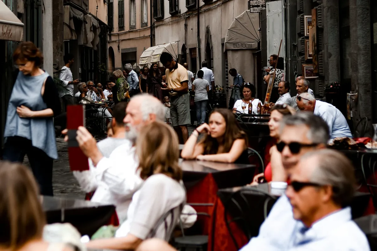 People enjoying coffee at outdoor street cafes in a historic Italian town